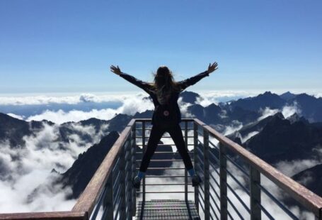 Success Stories - Person Standing on Hand Rails With Arms Wide Open Facing the Mountains and Clouds