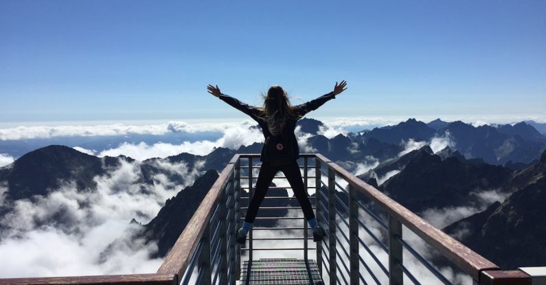 Success Stories - Person Standing on Hand Rails With Arms Wide Open Facing the Mountains and Clouds