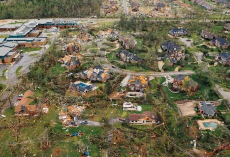 Consequences - Aerial view of tornado impact on small settlement cottages with destroyed roofs windthrown trees and bent electricity transmission lines