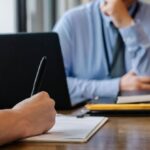 Accreditation Review - Crop anonymous female filling questionnaire when applying for job sitting in employer office