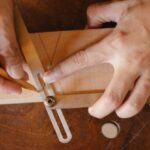 Master's Degrees - From above of crop anonymous craftsman using pencil and bevel gauge while working with wooden detail