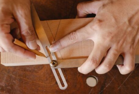Master's Degrees - From above of crop anonymous craftsman using pencil and bevel gauge while working with wooden detail