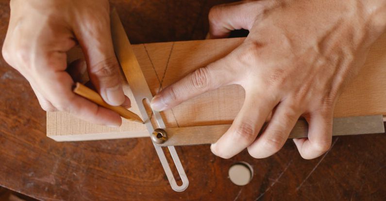 Master's Degrees - From above of crop anonymous craftsman using pencil and bevel gauge while working with wooden detail