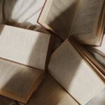 Academic Advising - From above opened paper books placed on comfortable bed with white disheveled sheets in daylight