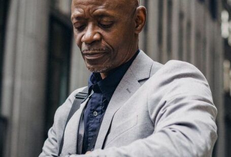 Time Management Tools - Busy black executive checking time on wristwatch on street