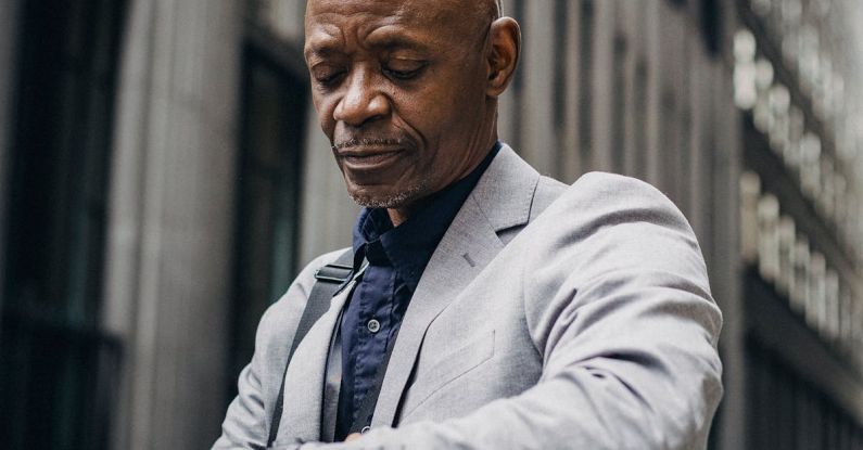 Time Management Tools - Busy black executive checking time on wristwatch on street