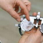 Doctorate Degree - Crop unrecognizable medic in white coat taking measuring vision glasses while adjusting scale according to numerals written on metal surface