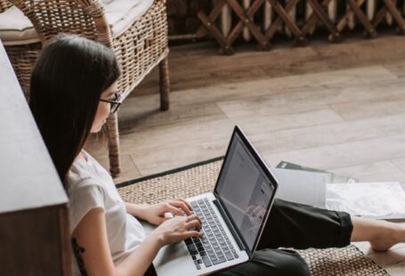 Work-Study Programs - Young barefoot woman using laptop on floor near books in stylish living room