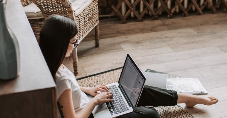 Work-Study Programs - Young barefoot woman using laptop on floor near books in stylish living room