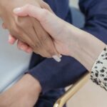 Associate Degrees - Crop anonymous multiracial female coworkers wearing formal clothes shaking hands in modern office