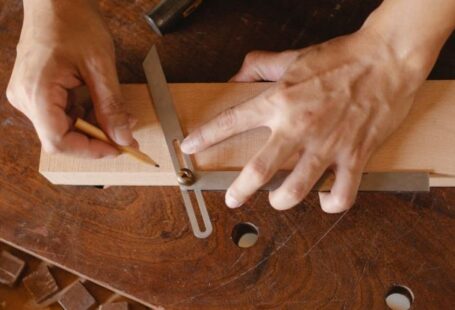 Business Degrees - High angle of skilled man using bevel tool and pencil while measuring angle of cut on workshop