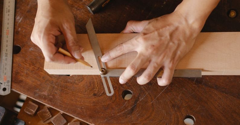 Business Degrees - High angle of skilled man using bevel tool and pencil while measuring angle of cut on workshop