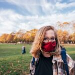 Scholarships - woman in black leather jacket wearing black sunglasses standing on green grass field during daytime