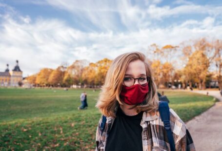 Scholarships - woman in black leather jacket wearing black sunglasses standing on green grass field during daytime