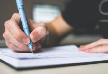 Essay Writing - Person Holding Blue Ballpoint Pen Writing in Notebook
